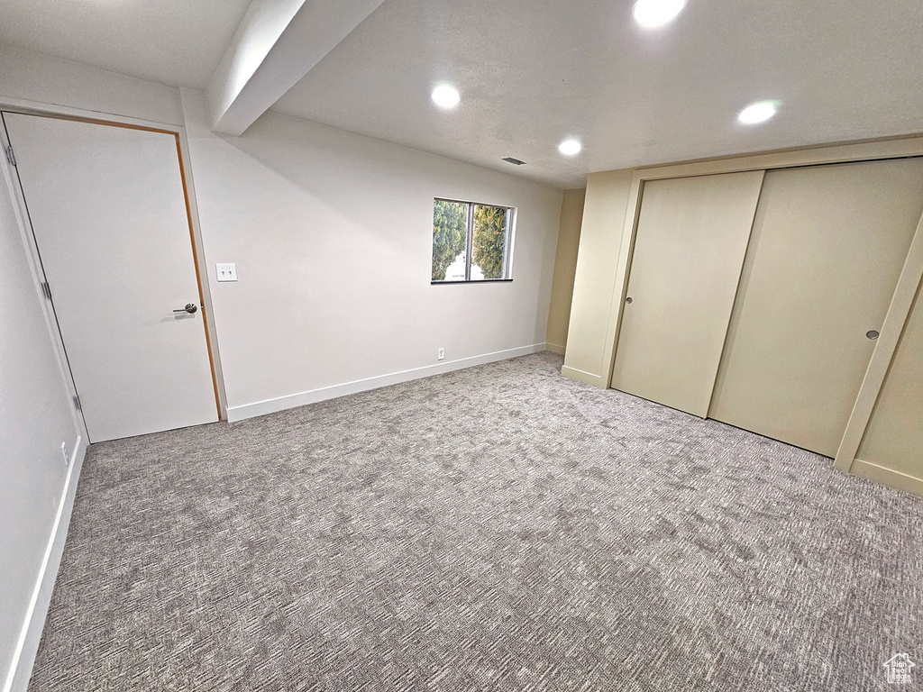 Unfurnished bedroom featuring beamed ceiling and carpet