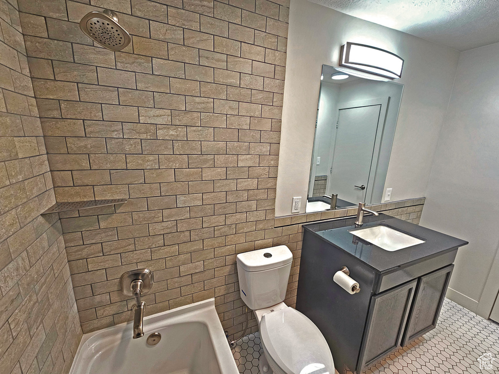 Full bathroom featuring tile patterned flooring, tiled shower / bath combo, vanity, a textured ceiling, and toilet