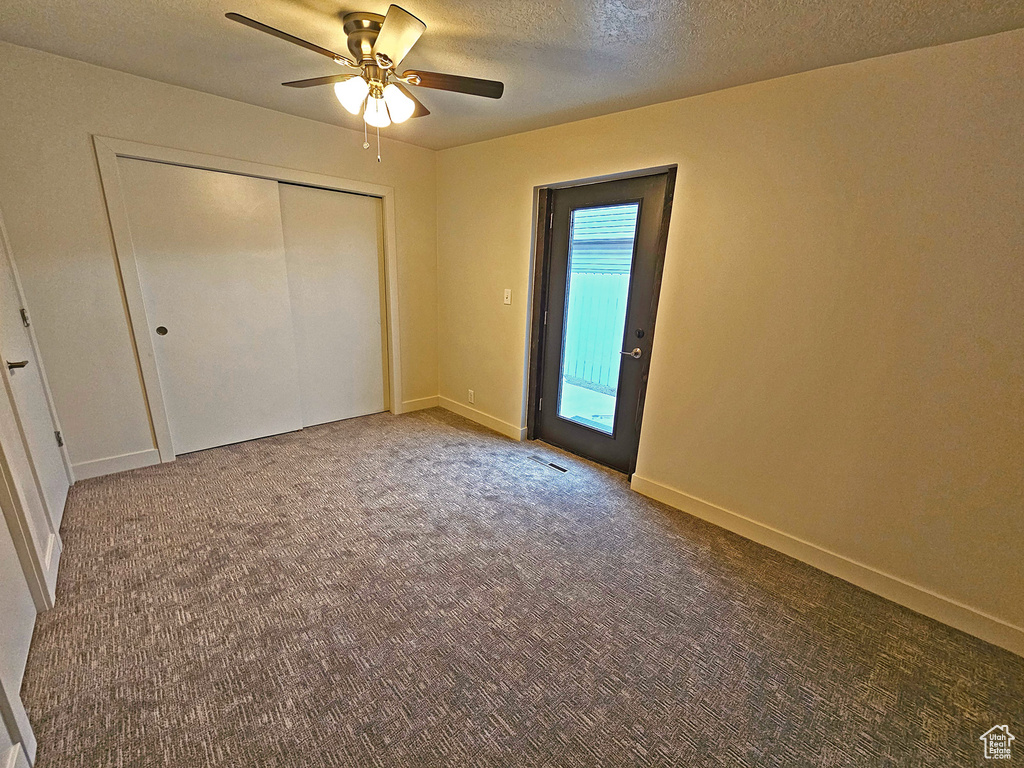 Unfurnished bedroom featuring carpet floors, a textured ceiling, ceiling fan, and a closet