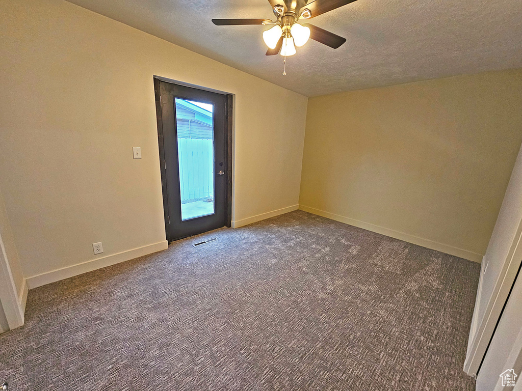 Spare room with vaulted ceiling, ceiling fan, carpet floors, and a textured ceiling