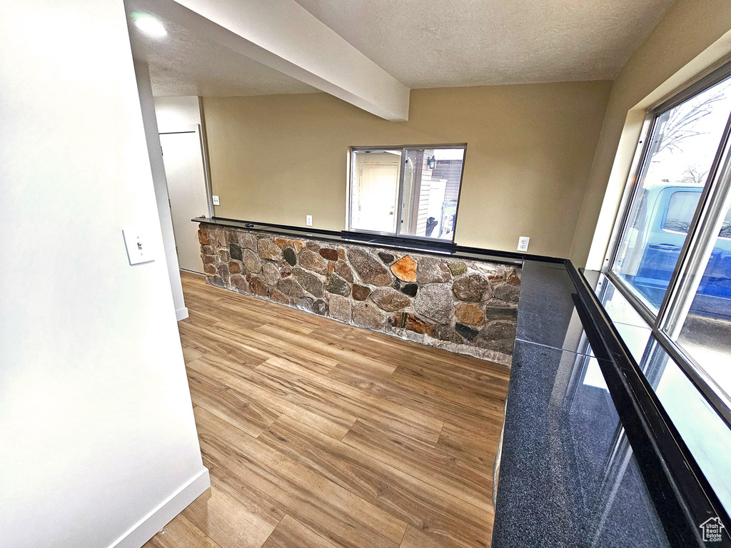 Interior space featuring beamed ceiling, wood-type flooring, and a textured ceiling