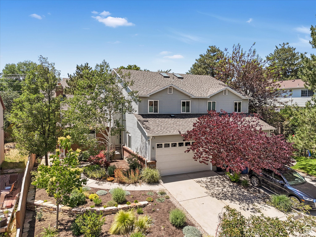 View of front facade featuring an attached garage, roof with shingles, and driveway