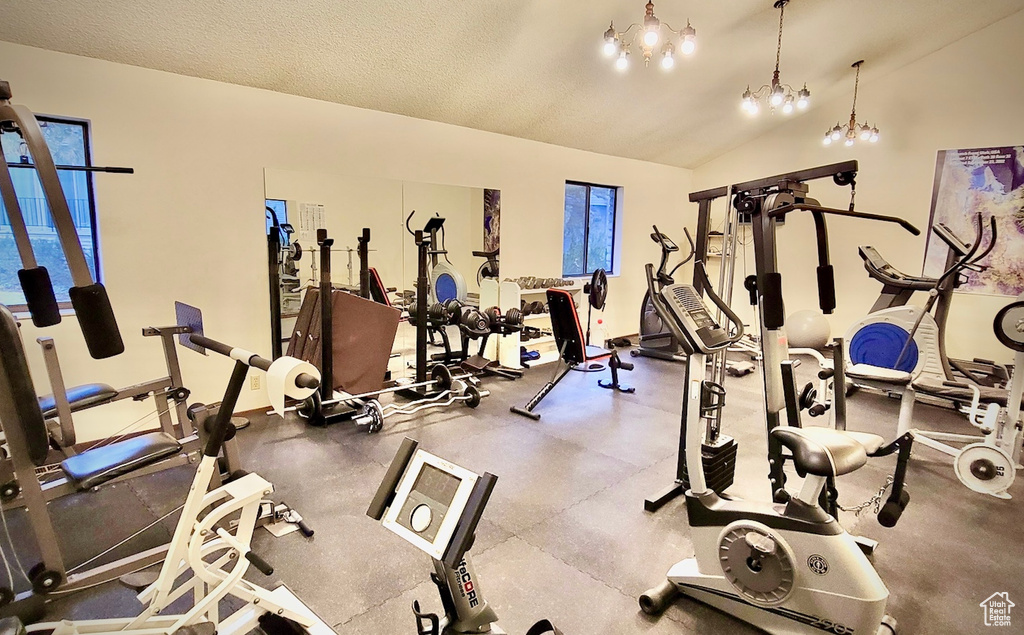 Workout area featuring a textured ceiling, an inviting chandelier, and lofted ceiling