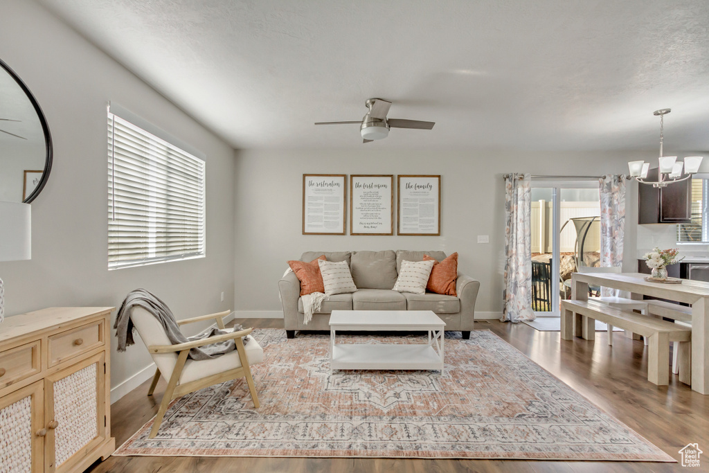 Living room with ceiling fan with notable chandelier, hardwood / wood-style flooring, and a healthy amount of sunlight