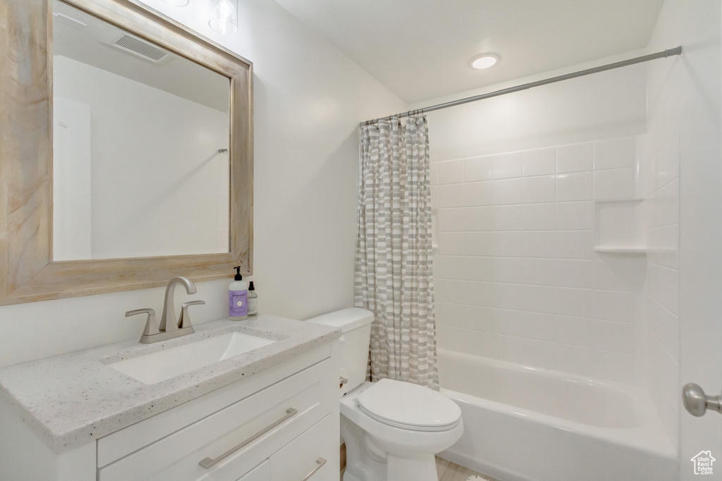 Full bathroom featuring vanity, shower / bath combo, and toilet