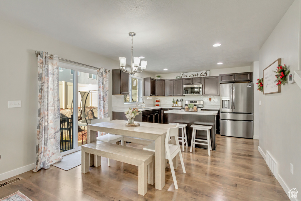 Dining area with sink, light hardwood / wood-style flooring, and a notable chandelier