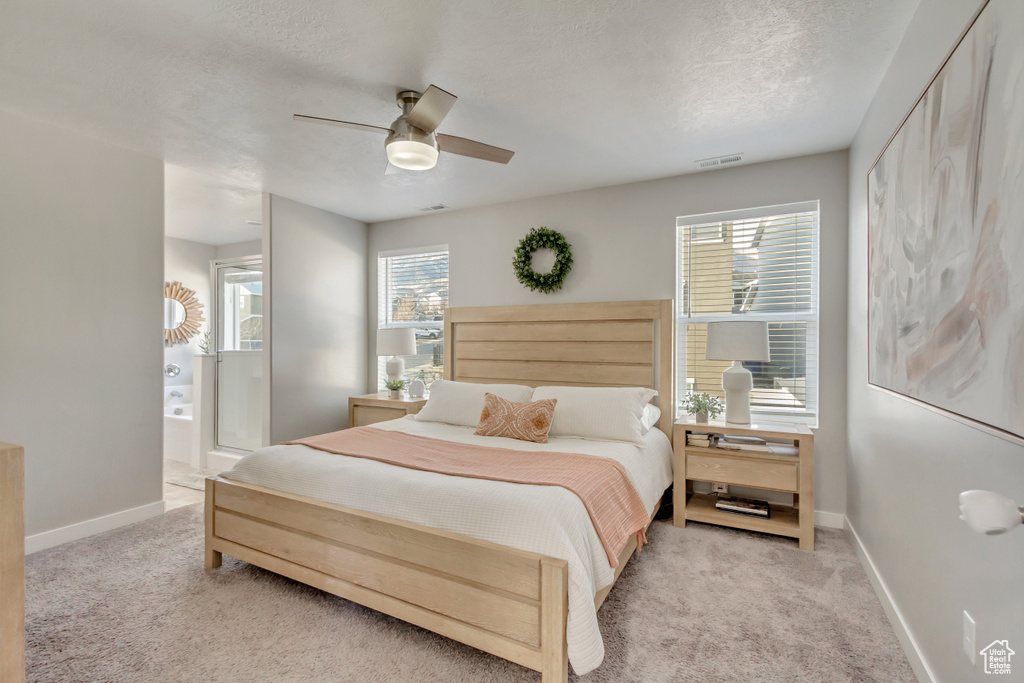 Carpeted bedroom with connected bathroom, ceiling fan, and a textured ceiling