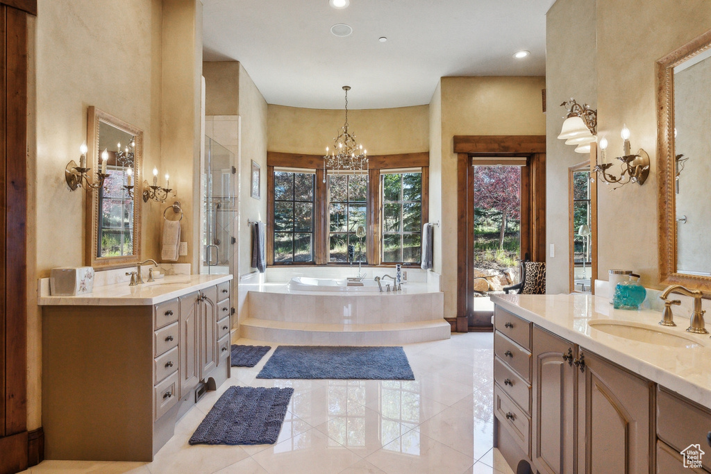 Full bath featuring two vanities, a bath, a chandelier, recessed lighting, and a shower with shower door
