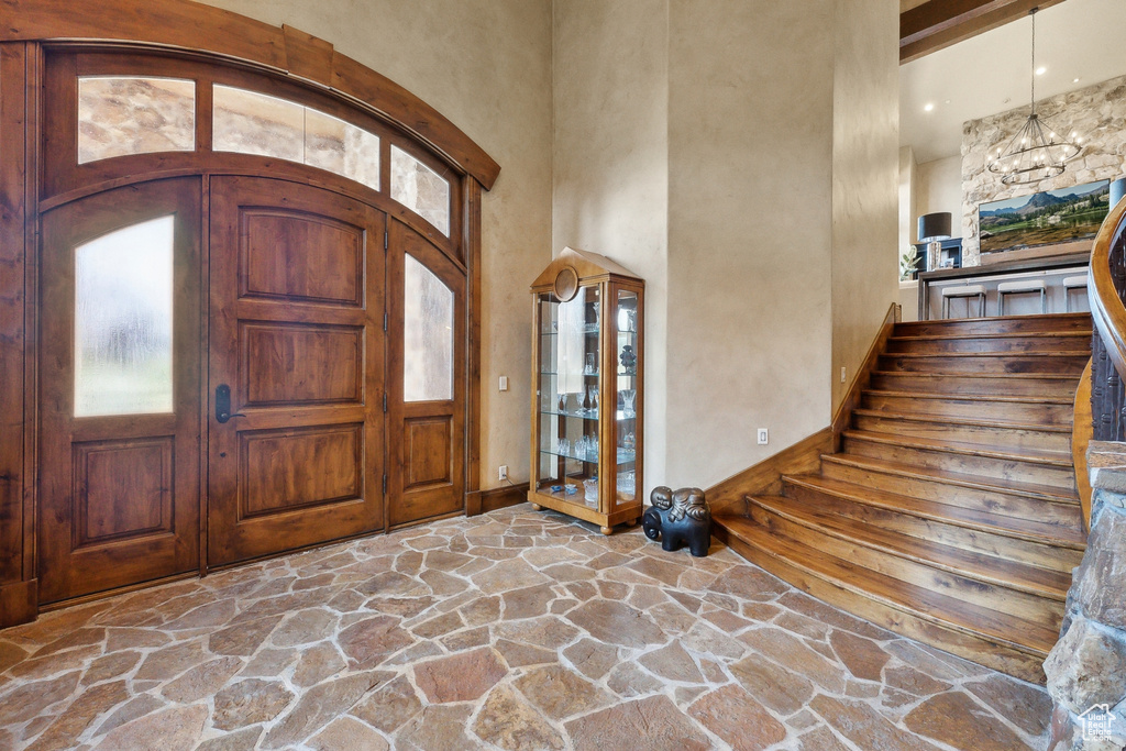 Foyer entrance featuring stone flooring, a towering ceiling, baseboards, and stairs