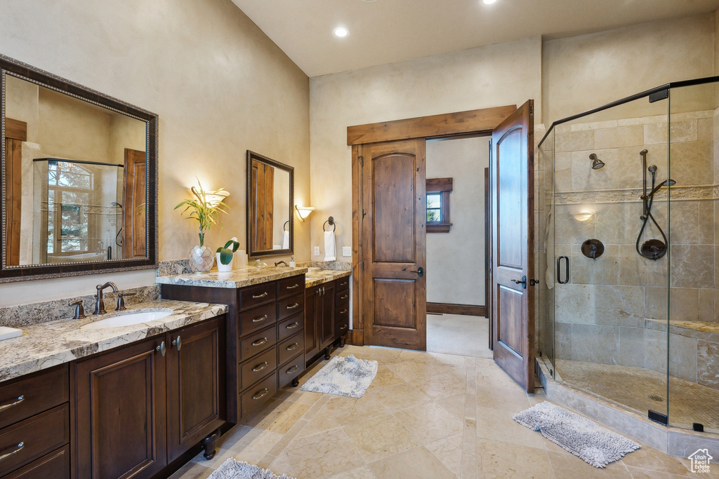 Bathroom with two vanities, a stall shower, recessed lighting, and baseboards