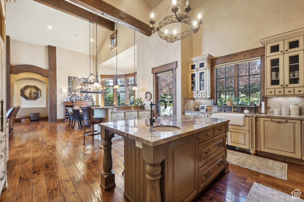 Kitchen featuring a sink, cream cabinetry, a chandelier, high vaulted ceiling, and dark wood-style flooring