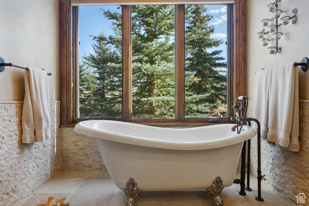 Bathroom featuring a freestanding tub, a wainscoted wall, and tile walls