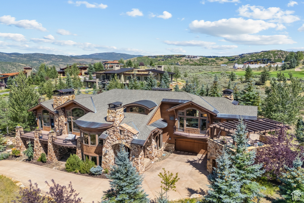 View of front of property with stone siding, an attached garage, a mountain view, and a chimney