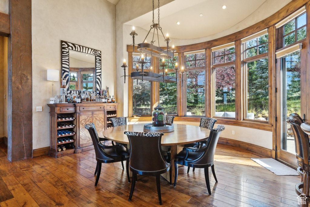Dining room with healthy amount of natural light, baseboards, hardwood / wood-style floors, and a towering ceiling