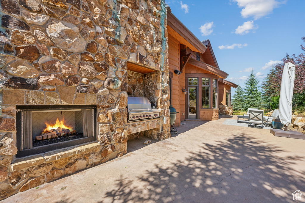 View of patio featuring grilling area and an outdoor stone fireplace