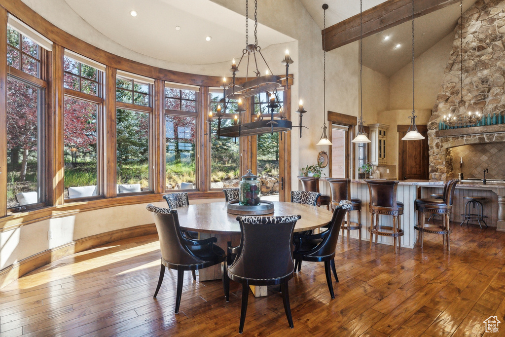 Dining space featuring high vaulted ceiling, hardwood / wood-style floors, and a chandelier