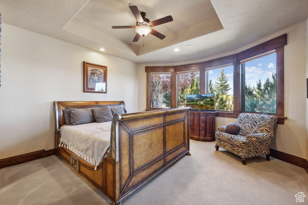 Bedroom featuring light colored carpet, baseboards, a raised ceiling, recessed lighting, and ceiling fan