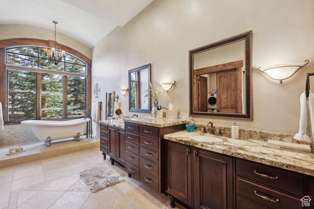 Bathroom featuring vanity, vaulted ceiling, a freestanding tub, and a chandelier