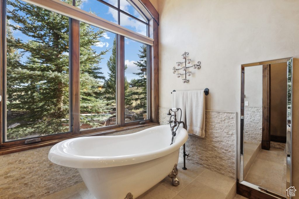 Bathroom featuring a soaking tub, tile walls, wainscoting, and tile patterned flooring