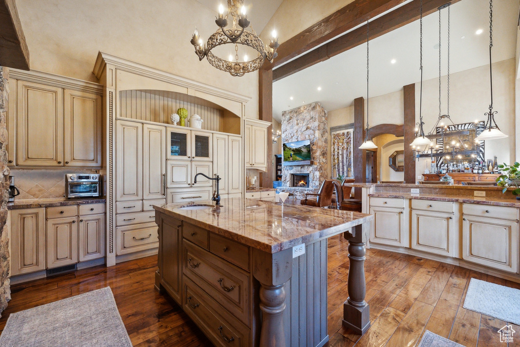 Kitchen featuring a sink, high vaulted ceiling, cream cabinets, a chandelier, and beam ceiling
