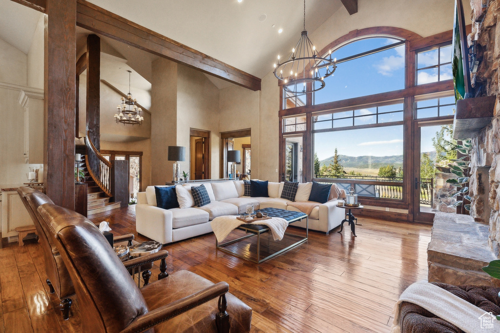 Living room featuring a chandelier, high vaulted ceiling, stairs, hardwood / wood-style flooring, and beamed ceiling