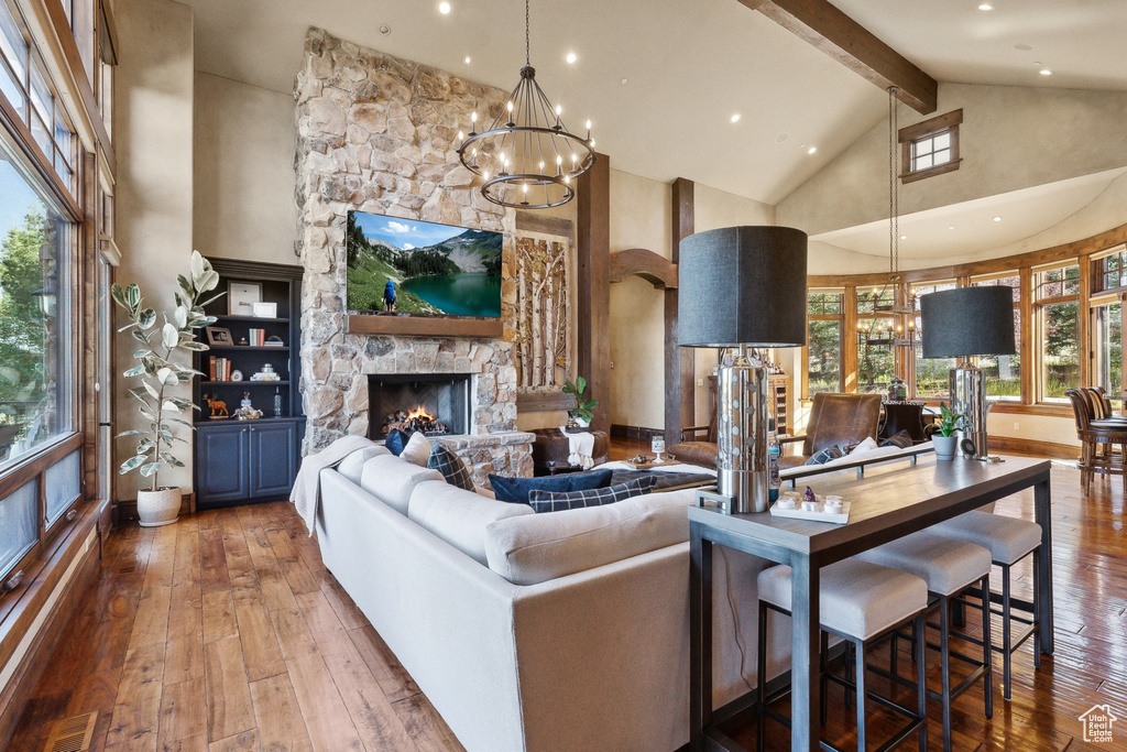 Living room with a chandelier, high vaulted ceiling, hardwood / wood-style floors, beamed ceiling, and plenty of natural light