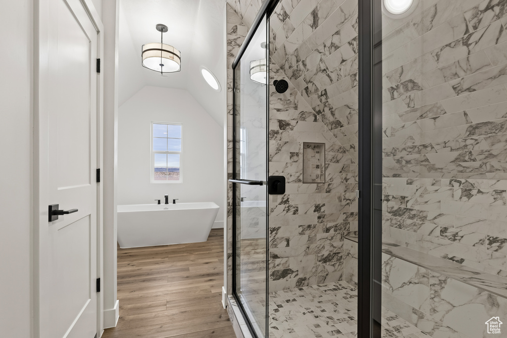 Bathroom with wood-type flooring, separate shower and tub, and vaulted ceiling