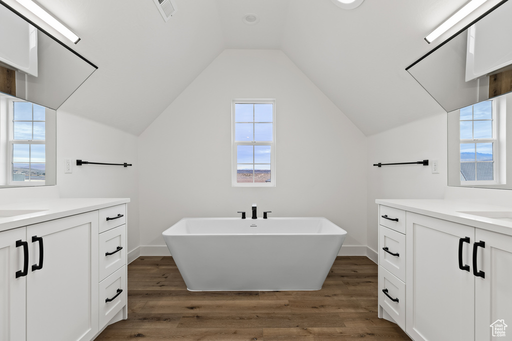 Bathroom featuring lofted ceiling, wood-type flooring, a bath, and vanity