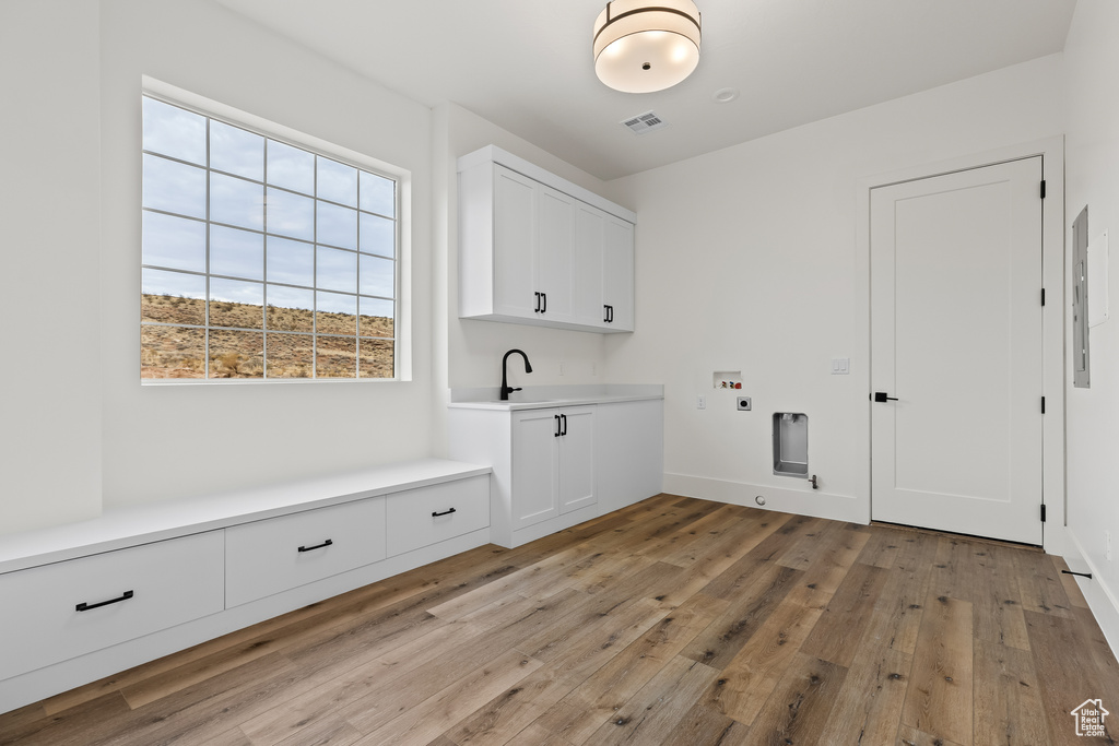 Washroom featuring cabinets, hookup for a washing machine, electric dryer hookup, sink, and light hardwood / wood-style floors