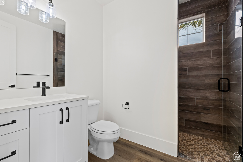 Bathroom with hardwood / wood-style floors, vanity, toilet, and a shower with door