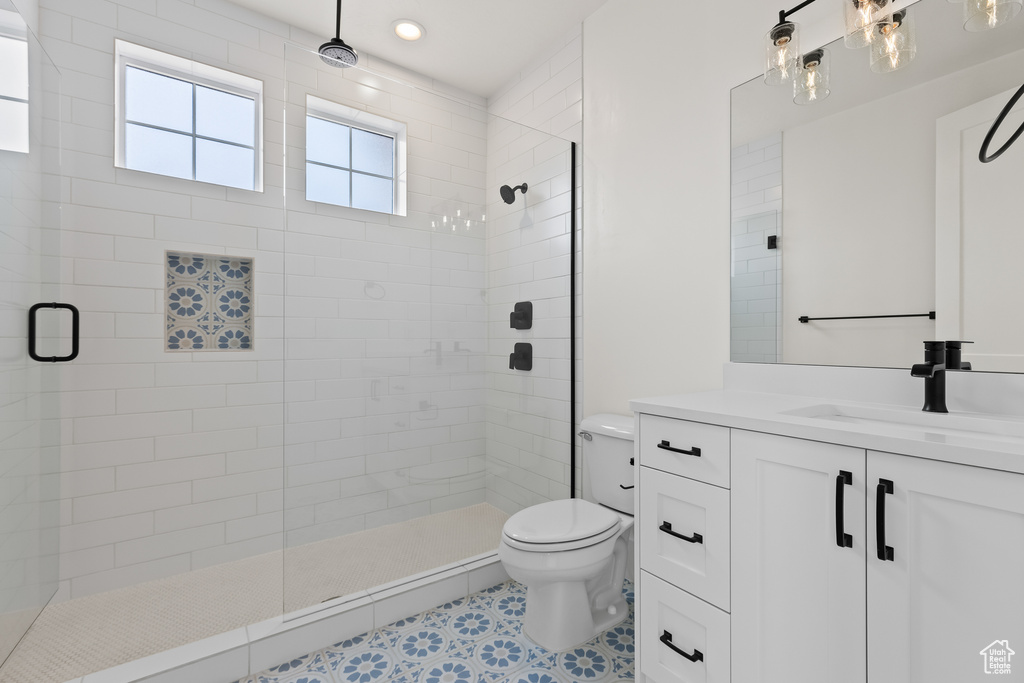 Bathroom featuring tile patterned floors, vanity, an enclosed shower, and toilet