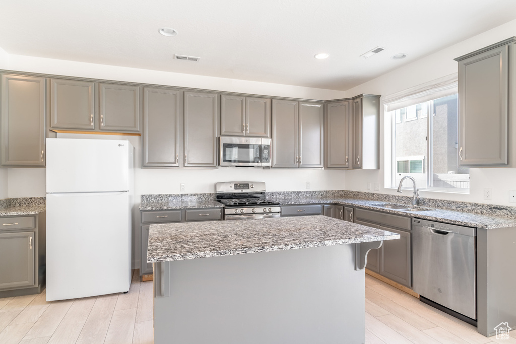 Kitchen with gray cabinets, sink, a kitchen island, and stainless steel appliances