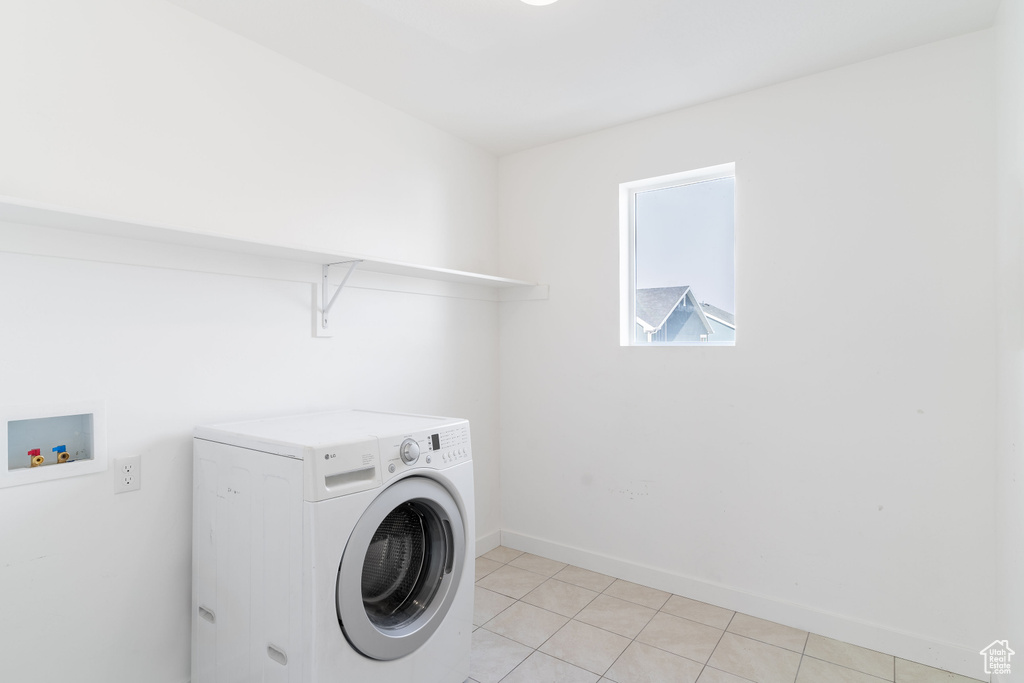 Clothes washing area featuring washer / dryer and light tile patterned floors