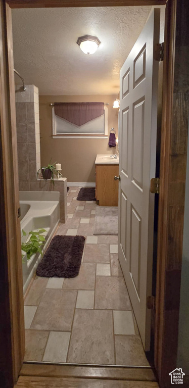 Full bathroom with stone tile floors, a shower, a textured ceiling, vanity, and a bath