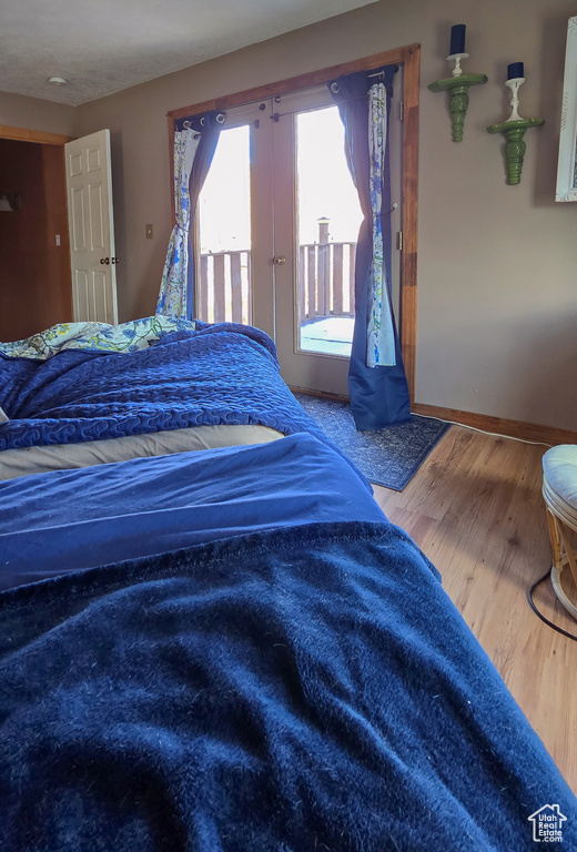 Bedroom featuring access to exterior, wood finished floors, and baseboards