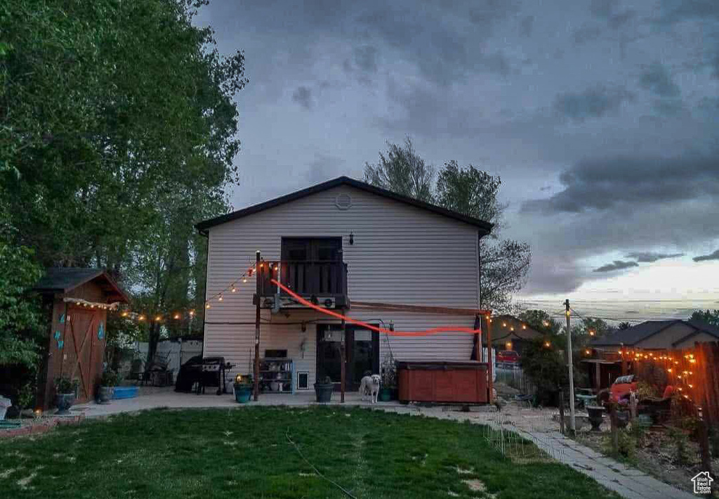 Back of house with a lawn, a patio area, a balcony, and a hot tub