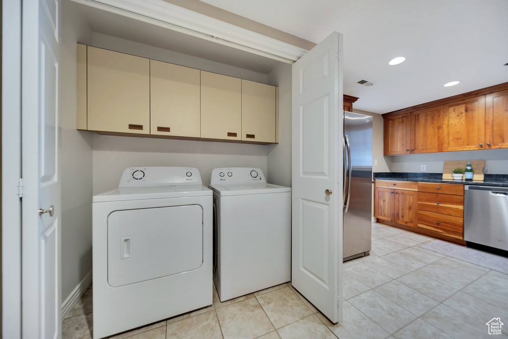 Washroom with cabinets, washing machine and dryer, and light tile patterned flooring