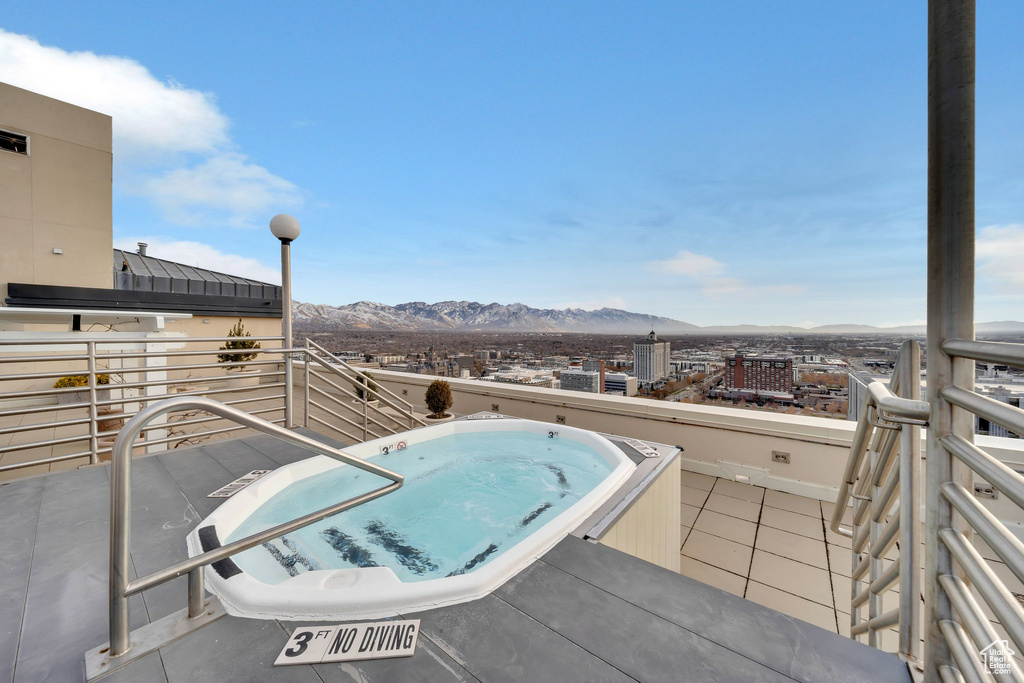 Exterior space with a mountain view, a balcony, and an in ground hot tub