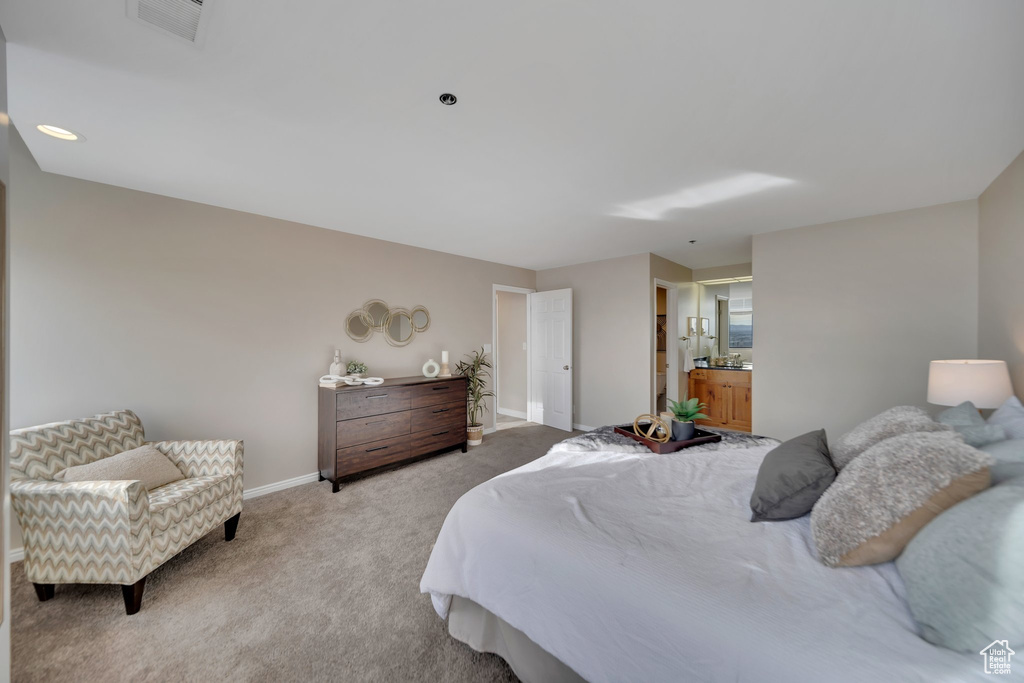 Bedroom featuring ensuite bathroom and light colored carpet