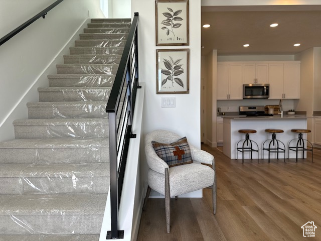 Stairway with wood finished floors and recessed lighting