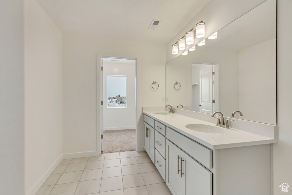 Bathroom with double vanity, a sink, tile patterned flooring, and visible vents