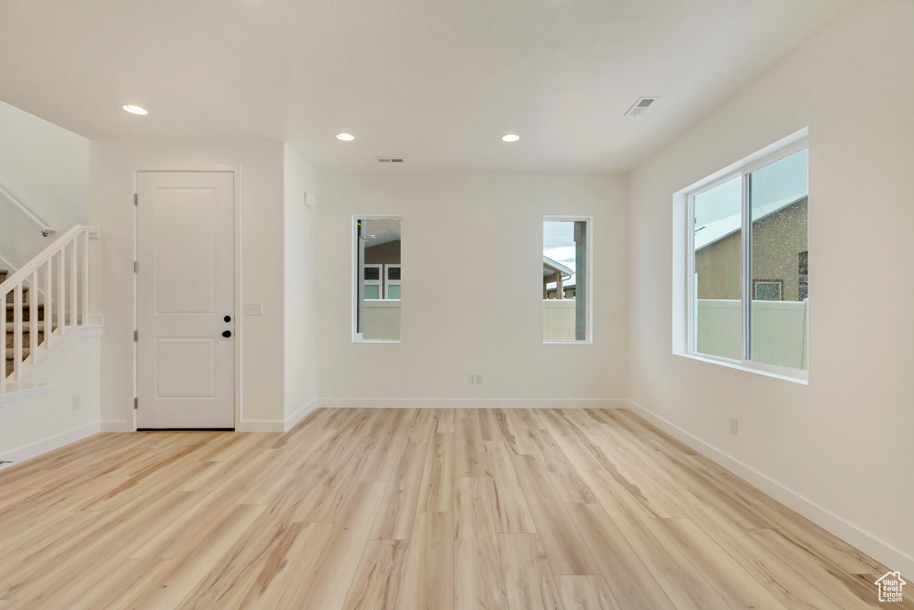 Spare room featuring baseboards, recessed lighting, light wood-style flooring, and stairway