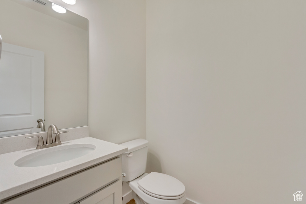 Bathroom featuring baseboards, toilet, and vanity