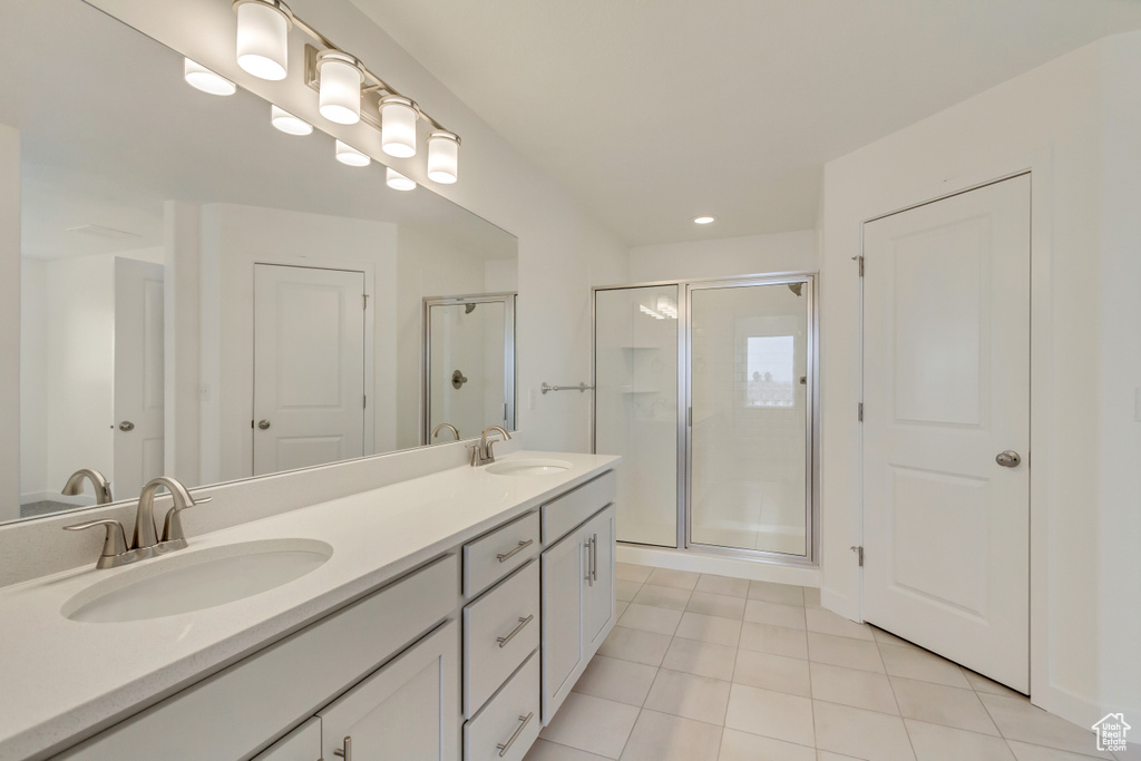 Full bathroom with a stall shower, double vanity, tile patterned flooring, and a sink