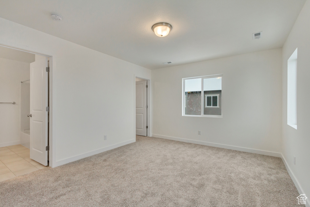 Spare room featuring light carpet, baseboards, and visible vents
