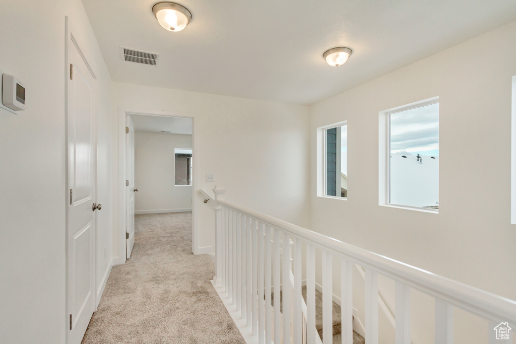 Corridor featuring light colored carpet and visible vents