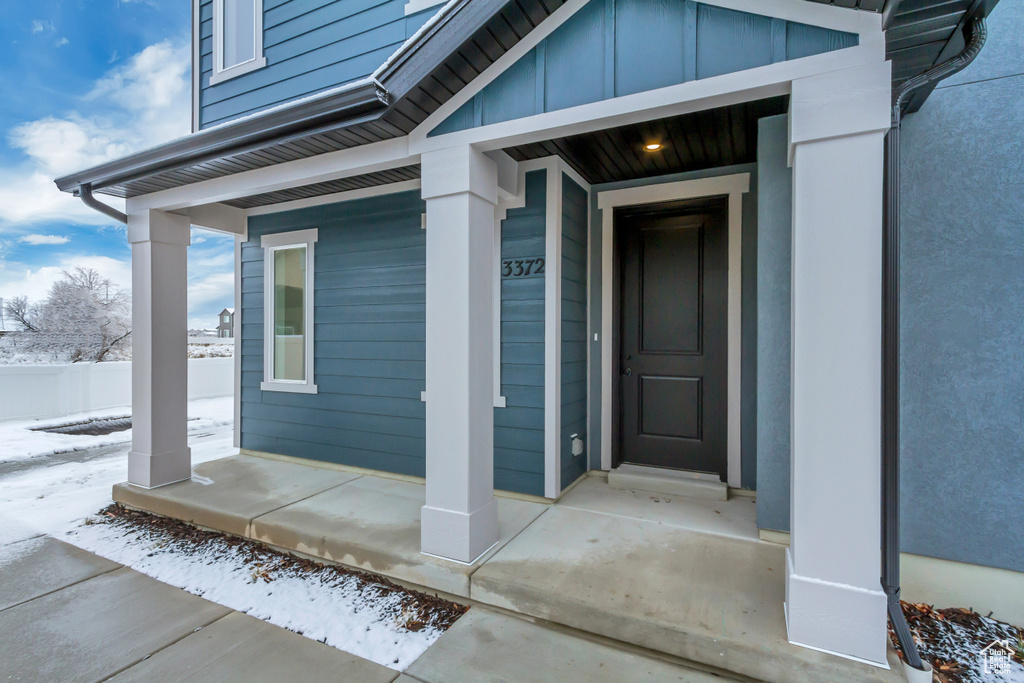 Snow covered property entrance with a porch