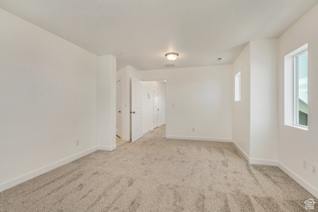 Empty room featuring light carpet, baseboards, and visible vents