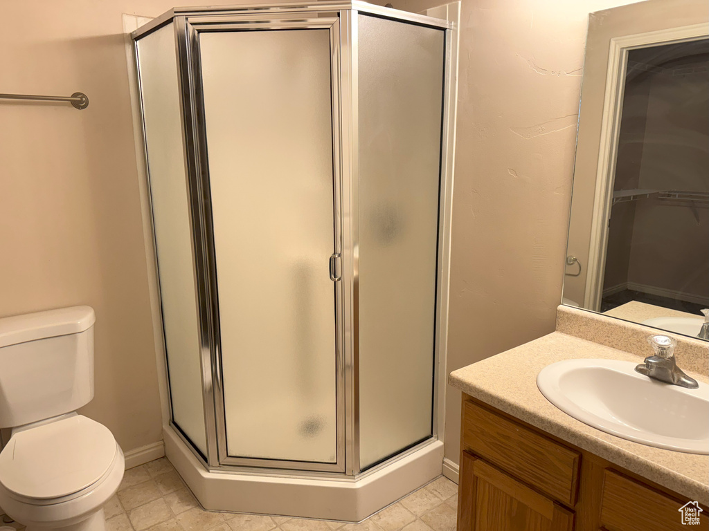 Bathroom featuring a shower with door, vanity, and toilet