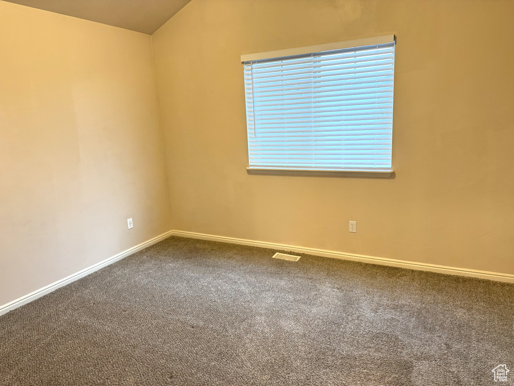 Empty room with carpet and vaulted ceiling